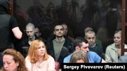 На задньому плані (за склом) ув’язнені українські громадяни в суді у російському Ростові-на-Дону, більшість із них – військовополонені, бійці полку «Азов». Росія, Ростов-на-Дону, 14 червня 2023 року