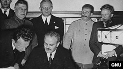 Vyaçeslav Molotov pakta imza atır. Arxada duranlar isə Ribbentrop və Stalindir - Moskva, 23 avqust 1939-cu il 