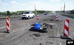 Легковушка проезжает мимо воронки от ударов. Антоновский мост в Херсоне, 21 июля 2022 года