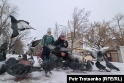 Петропавлдың орталығында кептерлерге жем шашып тұрған әйел мен бала. Солтүстік Қазақстан облысы, 19 желтоқсан 2020 жыл.