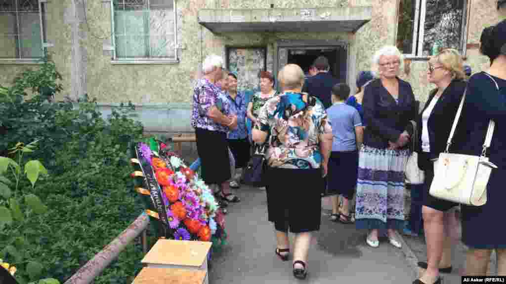 5 маусым күні &laquo;Паллада&raquo; қару-жарақ дүкені тұсынан өтіп бара жатқанда қаза тапқан тұрғын Николай Онищенкомен қоштасуға келген жұрт. Қару-жарақ дүкені бұл үйдің бірінші қабатына орналасқан. Ақтөбе, 8 маусым 2016 жыл.