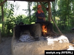 Лутсия Эралиева ауладағы ошақтың басында ас әзірлеп тұр.