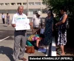 Атаберген деп баласының туған және өлген жылын жазған палкат көтерген оның әкесі Хасен Дүйсекенов. Жаңаөзен қаласы, 16 шілде 2012 жыл.