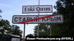 Дорожній вказівник міста Старий Крим. Вгорі історична кримськотатарська назва міста латиницею