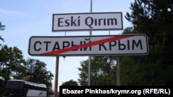 Дорожній покажчик міста Старий Крим. Вгорі історична кримськотатарська назва міста латиницею